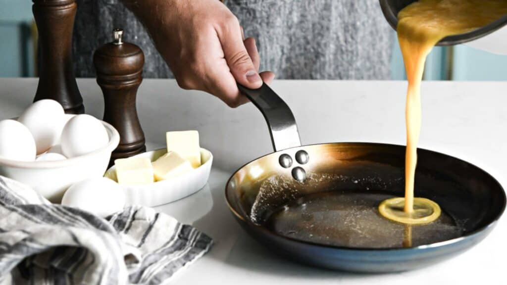 pouring eggs into carbon steel omelette pan